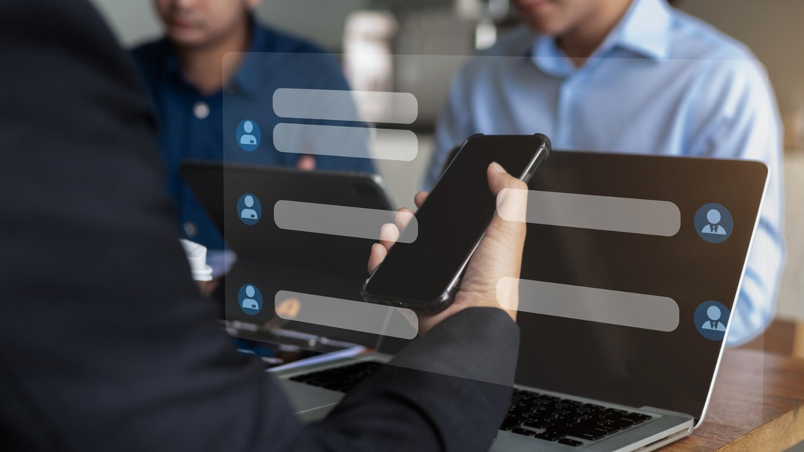 Person holding a smartphone in front of a laptop with chat bubbles overlaid, representing cross-platform chat services.